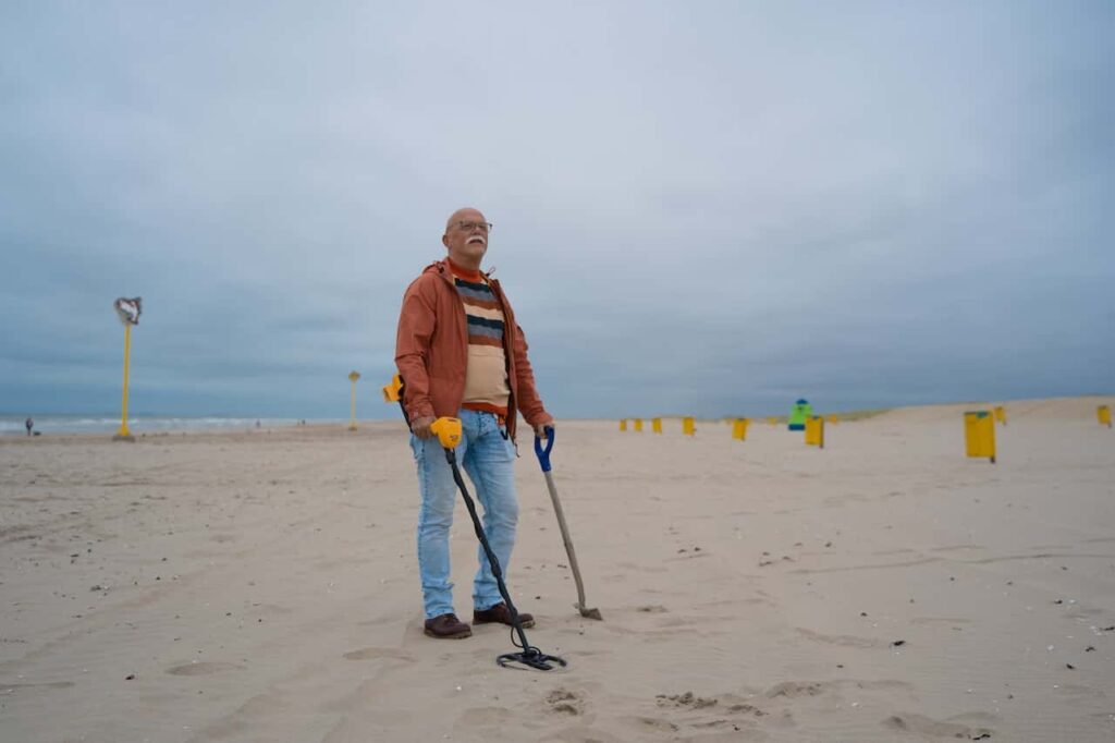mężczyzna szuka skarbów na plaży wykrywaczem metalu